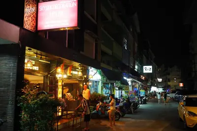 a city street at night with people sitting outside a restaurant at Sky Silk Decoration House in Patong Beach