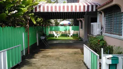 a green fence with chairs and an umbrella in a yard at Bangtao Kitchen Studio in Bang Tao Beach