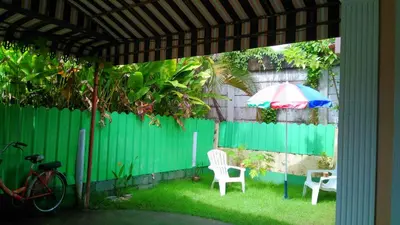 a patio with a green fence and an umbrella and chairs at Bangtao Kitchen Studio in Bang Tao Beach