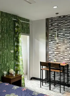 a bedroom with a table and a green wall at Bangtao Kitchen Studio in Bang Tao Beach