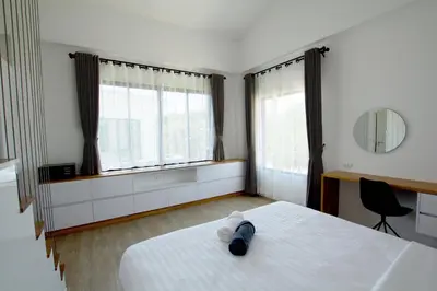 a bedroom with a white bed and two windows at Happy Family Villa in Phuket Town
