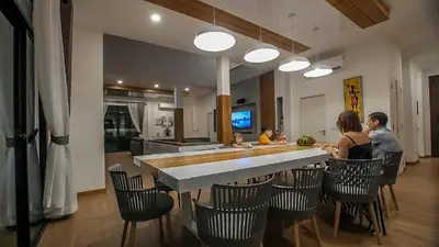a group of people sitting at a bar in a kitchen at Happy Family Villa in Phuket Town