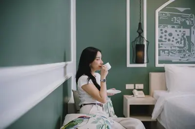a woman drinking a cup of coffee in a room at Peranakan House in Phuket Town