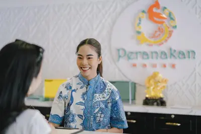 a woman talking to another woman in a room at Peranakan House in Phuket Town