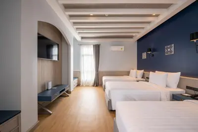 a hotel room with two beds and a blue wall at Seabed Grand Hotel Phuket in Phuket Town