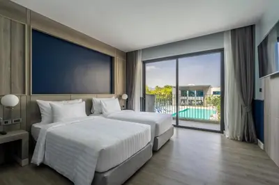 two beds in a bedroom with a view of a pool at Seabed Grand Hotel Phuket in Phuket Town