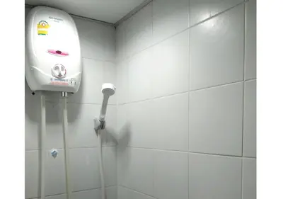 a shower with a soap dispenser on a white tile wall at Studio Sea View Patong in Patong Beach