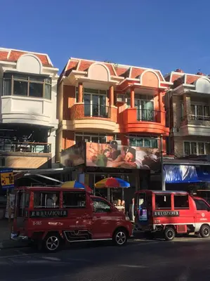 two red trucks parked in front of a building at PHADEE APARTMENT in Karon Beach
