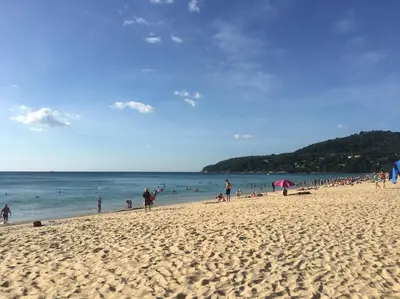 a group of people on a beach with the ocean at PHADEE APARTMENT in Karon Beach