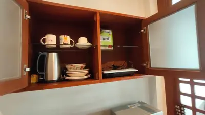 a kitchen with a cupboard with cups and dishes at PHADEE APARTMENT in Karon Beach