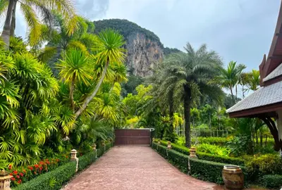 a garden with palm trees and a mountain in the background at Saifon Villas - Luxurious Pool Villas in Ao Nang Beach