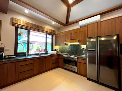 a kitchen with wooden cabinets and a stainless steel refrigerator at Saifon Villas - Luxurious Pool Villas in Ao Nang Beach