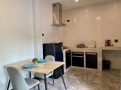 a kitchen with a wooden table with chairs and a black refrigerator at Blue Aura Pool Villa in Nai Yang Beach