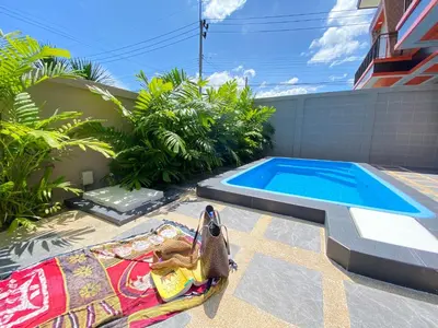 a swimming pool with a chaise lounge next to a house at Blue Aura Pool Villa in Nai Yang Beach