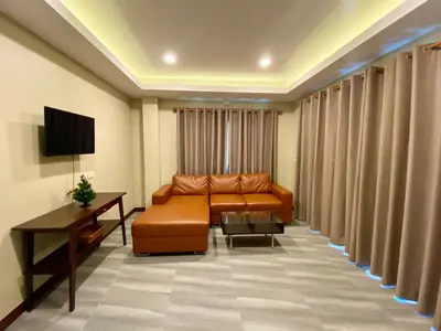 a living room with a couch and a television at Blue Aura Pool Villa in Nai Yang Beach