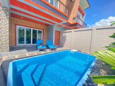 a swimming pool with two blue chairs next to a building at Blue Aura Pool Villa in Nai Yang Beach