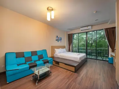 a bedroom with a blue couch and a bed at Naithon Beachfront Condotel in Nai Thon Beach