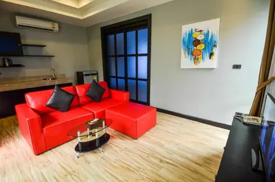a living room with a red couch and a table at Coco Paradiso Phuket SHA in Phuket Town