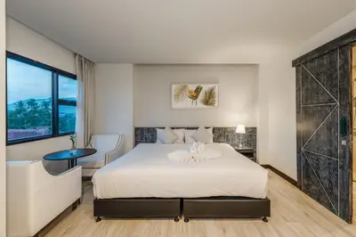 a bedroom with a large white bed and a table at Coco Paradiso Phuket SHA in Phuket Town