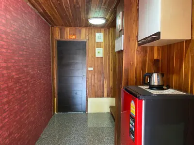 a kitchen with a black door and a red wall at Yuwadee Resort in Chalong