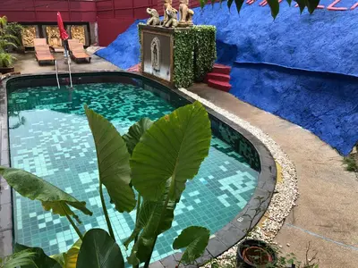 a swimming pool in a yard with a blue building at Baan Veerakit Hotel in Patong Beach