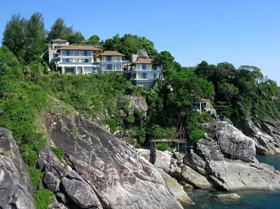 a house on a hill next to the water at Villa Minh in Kamala Beach