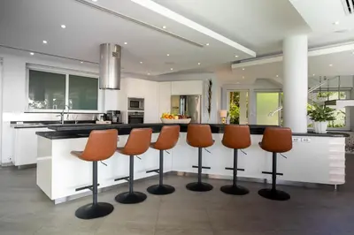a kitchen with a counter with four bar stools at Villa Beyond 9 Bedrooms Seaview - Full Services in Bang Tao Beach
