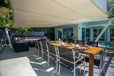 a table with chairs and an umbrella on a patio at Villa Beyond 9 Bedrooms Seaview - Full Services in Bang Tao Beach