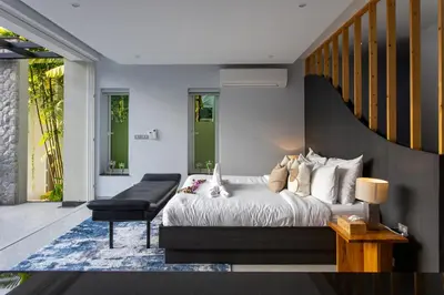 a bedroom with a bed and a chair and a staircase at Villa Namaste 7 Bedroom Fully Staffed Seaview Villa in Bang Tao Beach