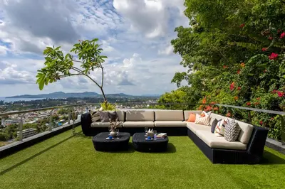 a patio with a couch and chairs on the grass at Villa Namaste 7 Bedroom Fully Staffed Seaview Villa in Bang Tao Beach