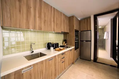a kitchen with wooden cabinets and a sink at Lets Phuket Twin Sands Resort & Spa in Patong Beach