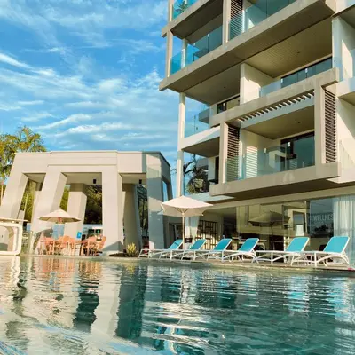 a swimming pool with chairs and umbrellas next to a building at Lets Phuket Twin Sands Resort & Spa in Patong Beach