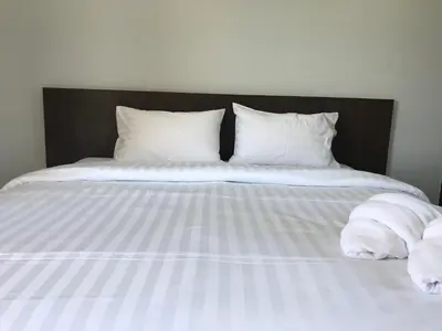 a bed with white sheets and pillows on it at G-HAN Residence in Nai Yang Beach