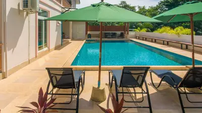 a pool with chairs and a table with an umbrella at Phuket9 Residence in Chalong