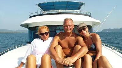 three people sitting on a boat on the water at Austrian Garden Hotel & Restaurant Patong in Patong Beach