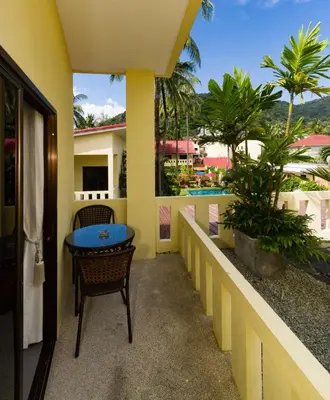 a balcony with a table and a view of a resort at Austrian Garden Hotel & Restaurant Patong in Patong Beach