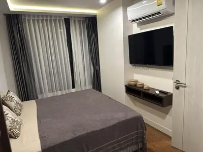 a bedroom with a bed and a flat screen tv at Unique loft 2-BR near of Surin Beach, private patio in Surin Beach