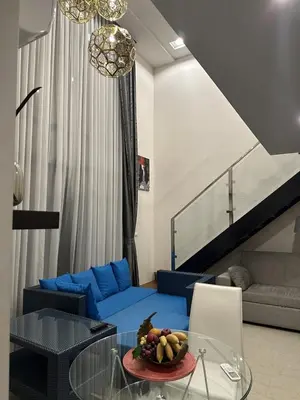 a living room with a blue couch and a glass table at Unique loft 2-BR near of Surin Beach, private patio in Surin Beach