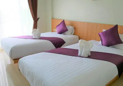 two beds in a hotel room with white and purple pillows at The Beach at Klong Muang in Klong Muang Beach