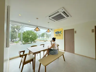 a woman sitting at a table in a room at Fishtail Hostel Phuket in Karon Beach