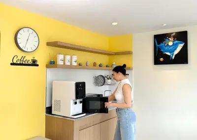 a woman standing in front of a counter with a microwave at Fishtail Hostel Phuket in Karon Beach