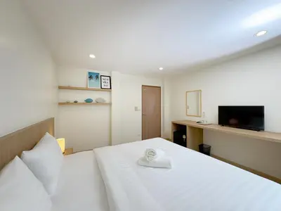 a bedroom with a white bed and a television at Fishtail Hostel Phuket in Karon Beach