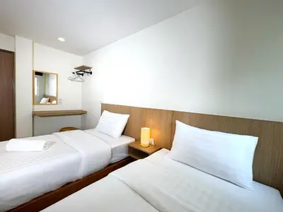 two beds in a hotel room with white sheets at Fishtail Hostel Phuket in Karon Beach