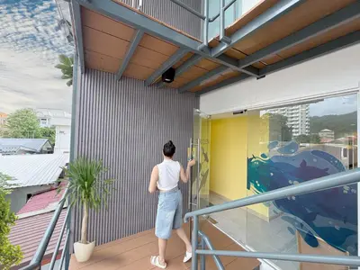 a person is painting a wall on a balcony at Fishtail Hostel Phuket in Karon Beach