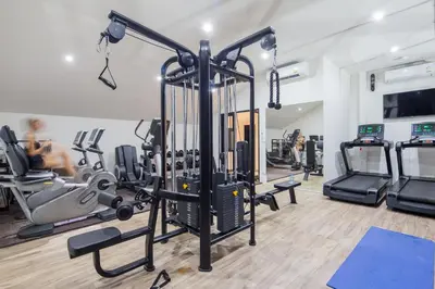a gym with cardio equipment and a woman in the background at Palmyrah Surin Beach Residence in Surin Beach