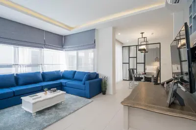 a living room with a blue couch and a tv at Palmyrah Surin Beach Residence in Surin Beach