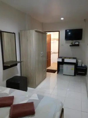 a living room with a wooden cabinet and a television at Living Room Guesthouse & Cafe Bar in Karon Beach