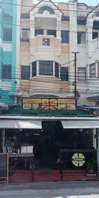 a store front of a building with a clock on it at Living Room Guesthouse & Cafe Bar in Karon Beach