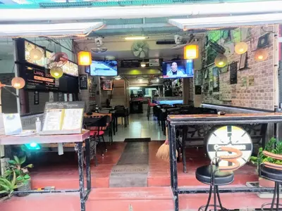 a restaurant with tables and chairs and a bar at Living Room Guesthouse & Cafe Bar in Karon Beach
