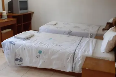a bedroom with two beds with white sheets and a tv at Praew Mansion in Kamala Beach